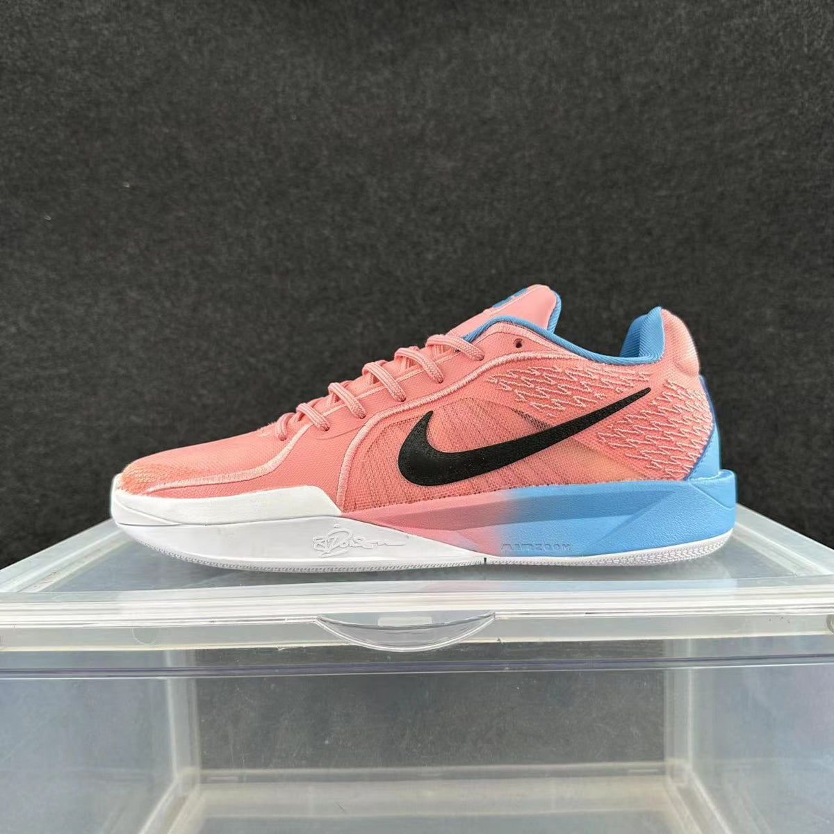Pink and blue low-top Nike basketball shoe with a black Swoosh, photographed from the side.