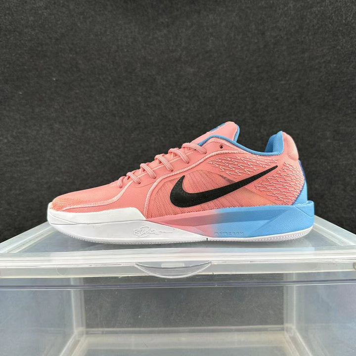 Pink and blue low-top Nike basketball shoe with a black Swoosh, photographed from the side.
