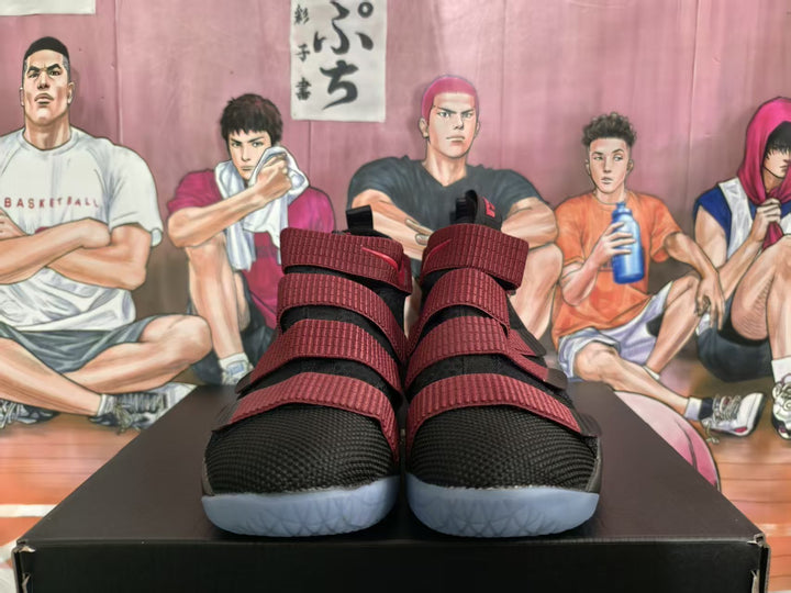 Front view of black and red Nike LeBron basketball sneakers with multiple red straps and light-colored outsoles.