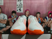 Front view of white Nike basketball shoes with orange outsoles, laces, and accents.