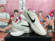 Pair of white Nike Kobe basketball shoes with black Swoosh details, shown from the side.
