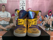 Front view of the purple and gold high-top basketball shoes with yellow laces and Kobe logos on the tongues.