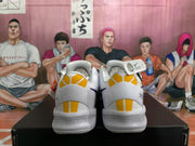 Rear view of white Nike basketball sneakers with purple and gold heel accents on a black shoebox.
