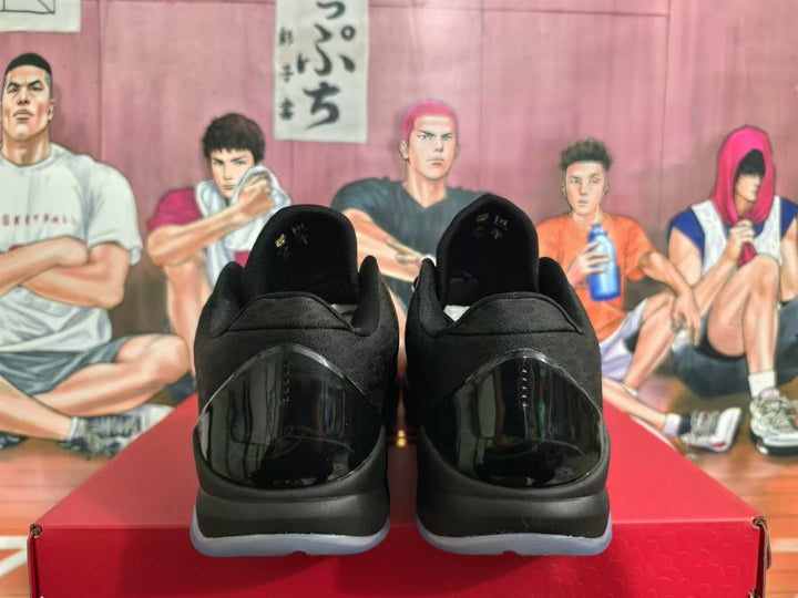 Rear view of black basketball sneakers with glossy heel panels and translucent outsoles on a red shoebox.