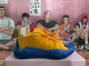 Side profile of a yellow and blue sneaker with orange laces, textured side detailing, and a blue outsole.