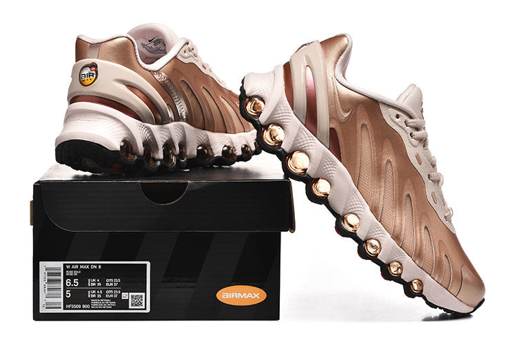 Rose-gold Nike Air Max DN 8 sneakers displayed with a box whose label shows sample size information.