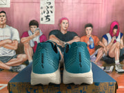 Rear view of teal Brooks Hyperion Max running shoes with white midsoles and a basketball-themed background