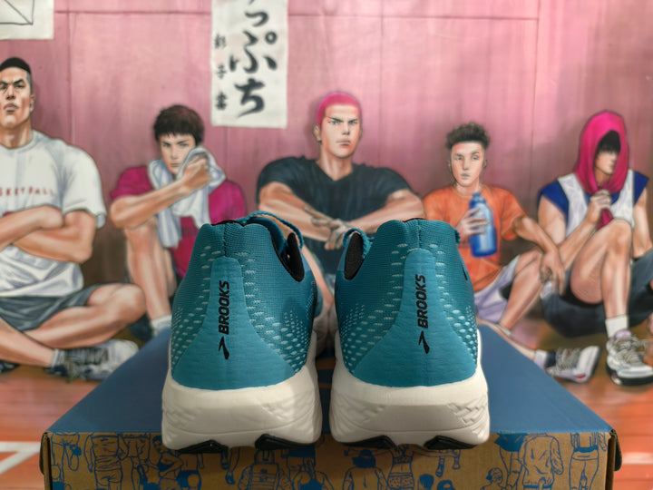 Rear view of teal Brooks Hyperion Max running shoes with white midsoles and a basketball-themed background