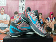 Pair of gray, black, blue, and red basketball sneakers displayed on a box, showing the patterned upper and blue side detailing.