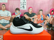 Side view of a black and white Nike basketball sneaker showing the layered upper, black Swoosh, and thick white midsole.