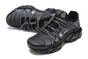 Angled view of a pair of black and grey Nike Air Max Plus sneakers with cord-style laces.