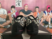 Rear view of black Converse sneakers with leopard-print heel panels and pink Converse branding.