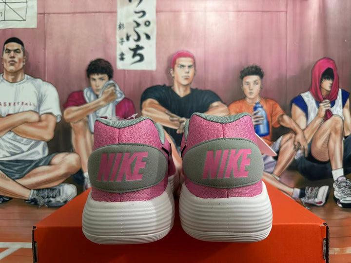 Rear view of pink and grey Nike sneakers with white ridged outsoles.