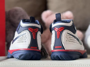 Rear view showing red basketball-inspired heel emblems, navy collars, and textured outsoles.