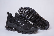 Black Nike-style sneaker pair with one shoe showing the segmented outsole.