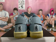 Rear view of blue-gray Nike sneakers showing the heel panels, pull tabs, and yellow-toned outsoles.