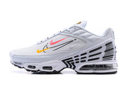 Side profile of a white Nike Air Max Plus sneaker with black geometric accents and visible cushioning.