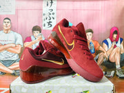 Angled view of burgundy Nike basketball shoes with gold Swoosh accents and translucent heel sections