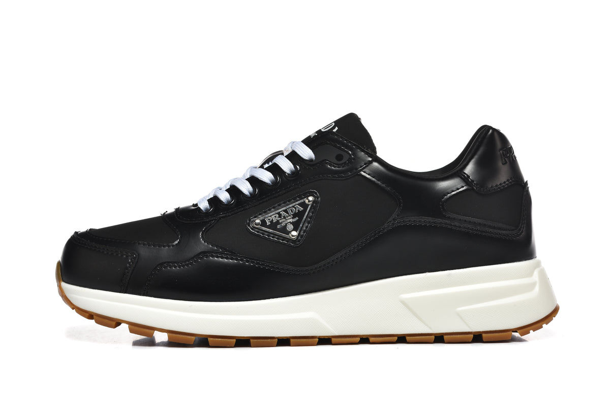 Side view of a black low-top lace-up sneaker with a triangular side plaque, off-white midsole, and gum-colored outsole.