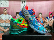 Two mismatched Nike basketball shoes displayed together, one orange and green and the other blue and orange
