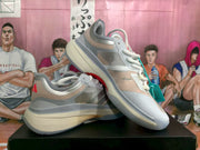 Side view of layered gray, pale blue, and pink adidas basketball shoes with white laces.