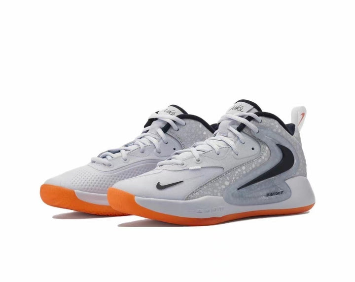Pair of gray Nike sneakers with black Swoosh branding, white laces, gray patterned side panels, and bright orange outsoles.
