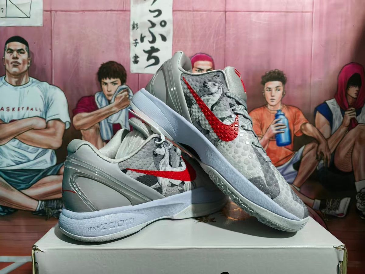 Pair of grey and red Nike Zoom sneakers displayed on a shoebox, showing the textured upper, red Swoosh, and layered midsole.