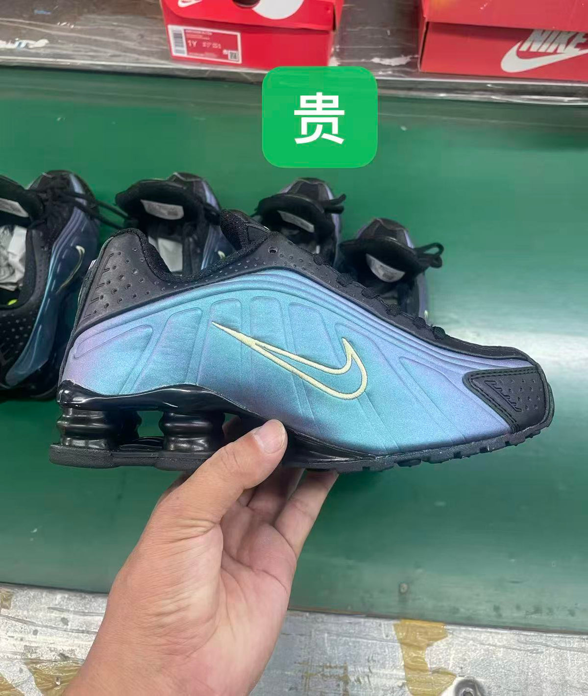 Side view of a blue iridescent Nike Shox-style sneaker with black accents and visible heel columns.