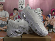 Angled view of a pair of white Nike sneakers with lace-up fastening, padded collars, and oval sole accents.