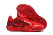 Red basketball sneakers displayed with one shoe lifted to reveal the textured rubber outsole.