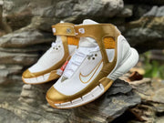 Angled front view of the white and metallic-gold sneakers