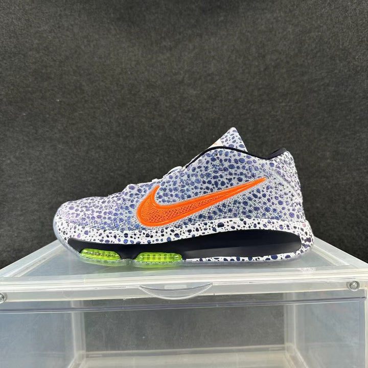 Side view of white and blue speckled Nike sneakers with an orange logo and lime-green cushioning details
