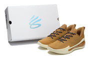 Brown sneakers displayed beside a white shoebox, showing the cream outsole and translucent heel details.