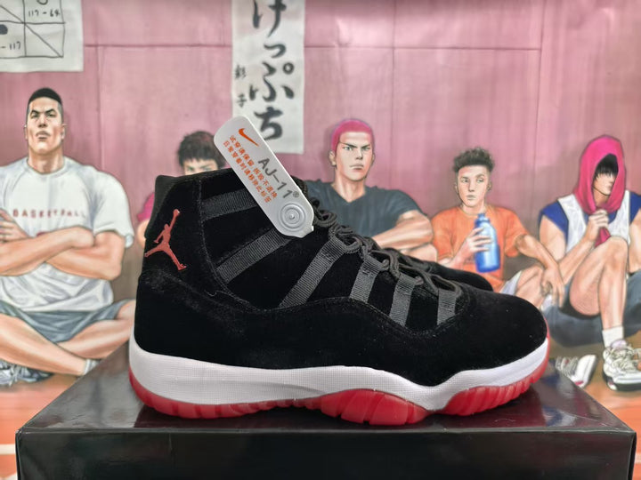 Side view of a black high-top basketball sneaker with red branding, a white midsole, and a translucent red outsole on a black box.