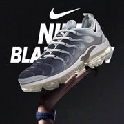 Angled view of grey and black Nike Air VaporMax Plus sneakers with a transparent segmented sole