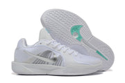 White basketball shoes with one shoe turned to show the patterned outsole and teal accents.