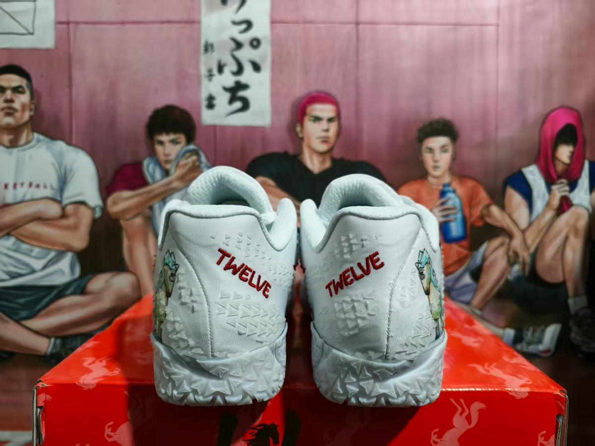 Rear view of white Nike basketball sneakers with red TWELVE lettering, textured midsoles, and animal graphics at the sides.