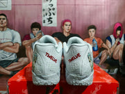 Rear view of white Nike basketball sneakers with red TWELVE lettering, textured midsoles, and animal graphics at the sides.