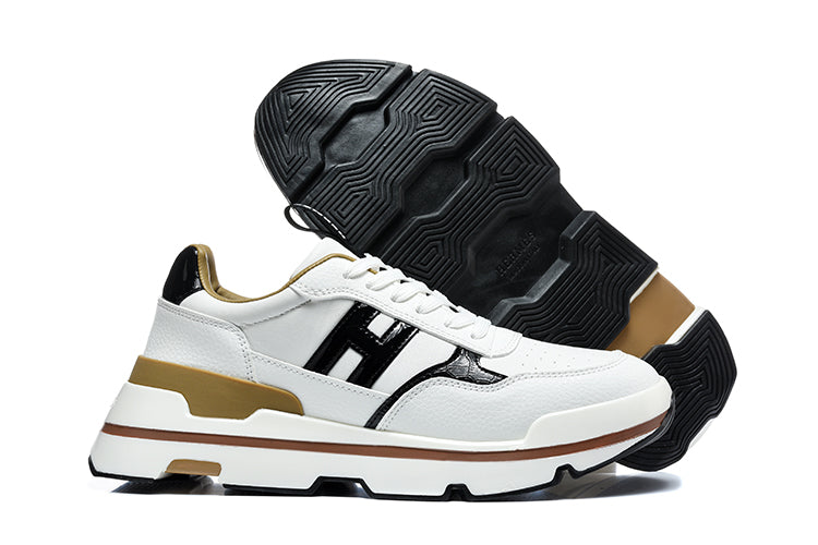 White low-top sneakers with black side panels and tan-gold accents, shown from the side with the black tread outsole visible.