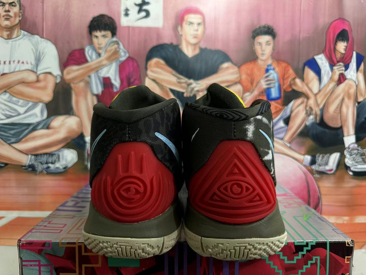 Rear view of dark basketball shoes with red heel pieces, light blue logo details, and a patterned outsole.