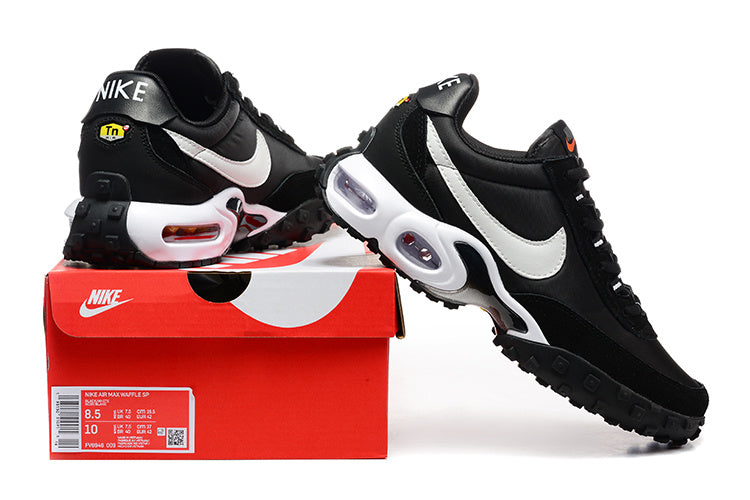 Black and white Nike Air Max Plus SE sneakers displayed with a red shoebox; the box label shows size markings.