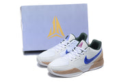 Jordan sneaker pair displayed in front of a branded shoebox, showing the white, blue, tan-gold, and dark green color combination.