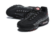 Angled view of black and grey Nike Air Max 95 sneakers with red accents and visible sole cushioning.