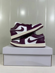 Two burgundy and white low-top sneakers arranged on a shoebox, showing the side panels and soles.