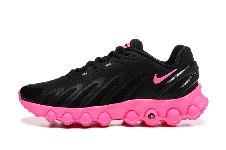 Side view of black sneakers with pink accents and a sculpted pink bubble-pattern sole