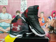 Angled view of the black and red high-top basketball sneakers showing the layered upper, heel panels, lace system, and textured outsole.