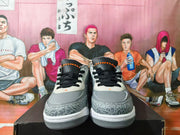 Front view of grey Jordan low-top sneakers with black laces and patterned toe overlays