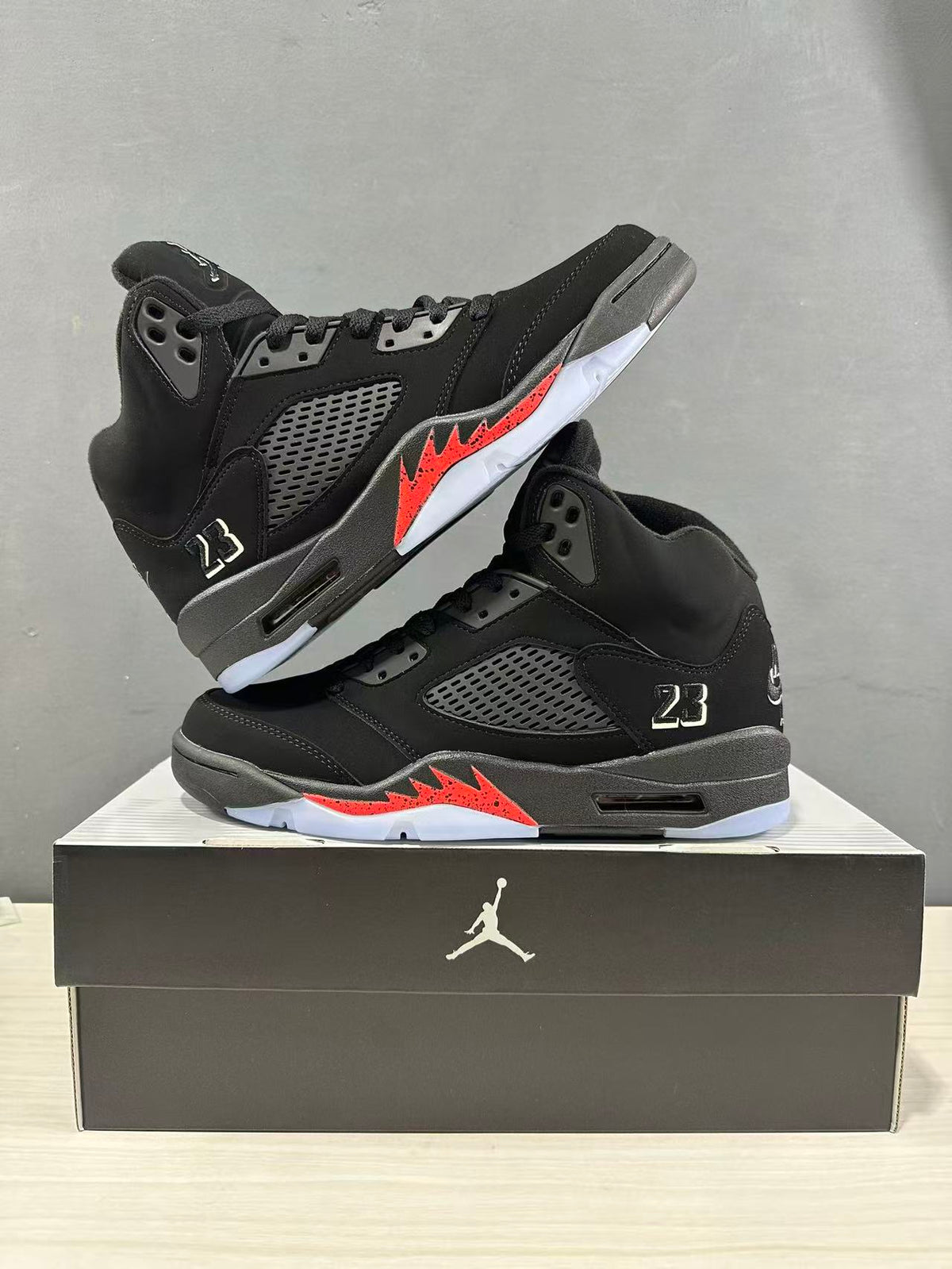 Pair of black and red Jordan Air Jordan 5 Retro high-top sneakers displayed on a black shoebox