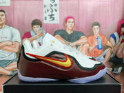 Side view of a white and dark red basketball shoe with a gold side logo and translucent-looking outsole