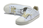 White low-top sneakers shown from above at an angle, highlighting the mixed-color laces and textured toe caps.